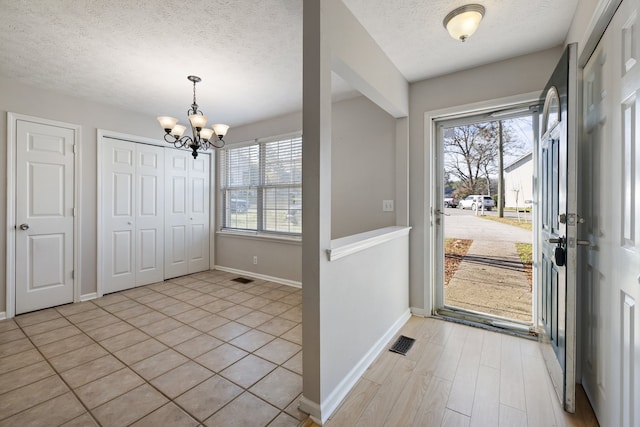 tiled foyer with a textured ceiling, a wealth of natural light, and a notable chandelier