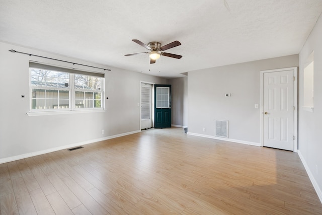 unfurnished room with a textured ceiling, light wood-type flooring, and ceiling fan