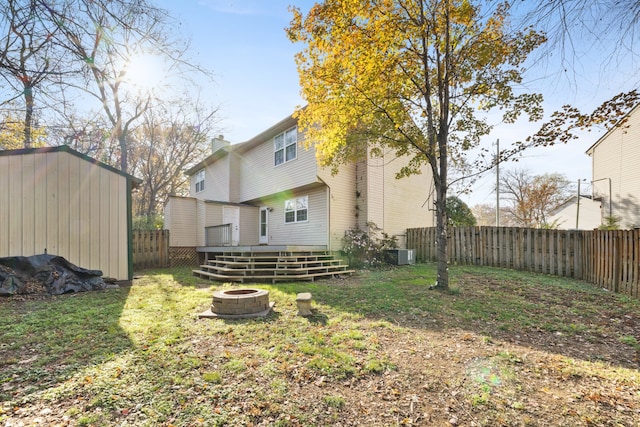 view of yard featuring a storage unit, cooling unit, an outdoor fire pit, and a wooden deck