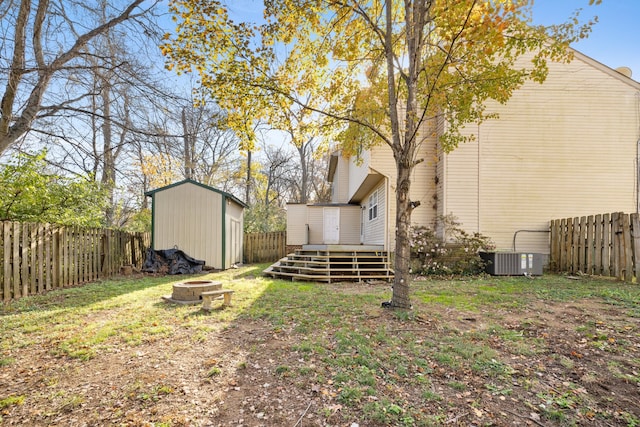 view of yard with central AC, a deck, a storage unit, and a fire pit