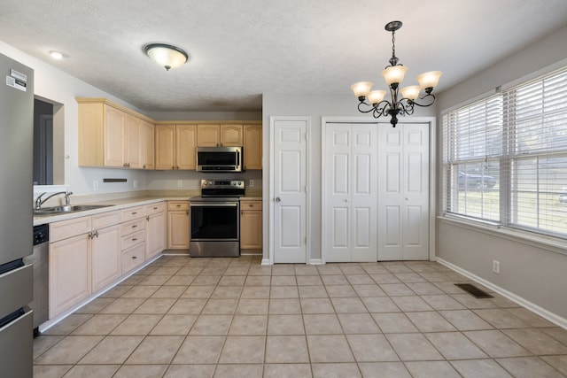 kitchen featuring sink, stainless steel appliances, light brown cabinetry, and a chandelier