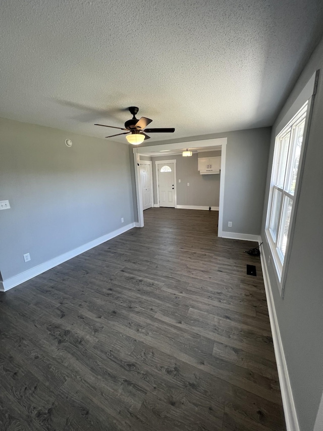 unfurnished living room with a textured ceiling, ceiling fan, and dark wood-type flooring