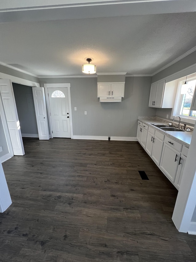 kitchen with a textured ceiling, crown molding, dark wood-type flooring, sink, and white cabinets