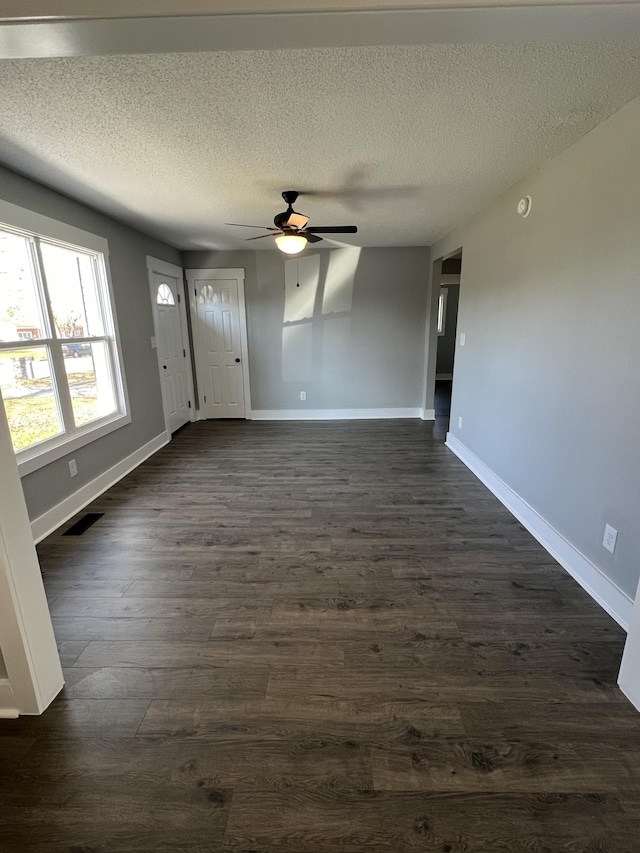 interior space with a textured ceiling, ceiling fan, and dark wood-type flooring