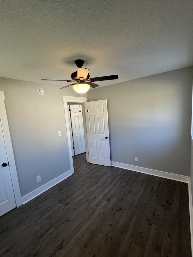 unfurnished bedroom with a textured ceiling, dark hardwood / wood-style floors, and ceiling fan