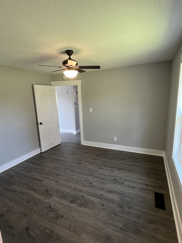 unfurnished room featuring a textured ceiling and dark hardwood / wood-style floors