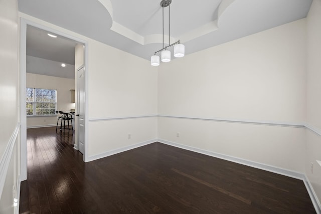 spare room with a raised ceiling and dark hardwood / wood-style flooring