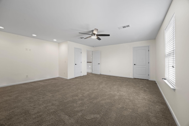 unfurnished bedroom featuring ceiling fan, dark carpet, and multiple windows