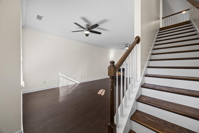 stairs with ceiling fan, wood-type flooring, and crown molding