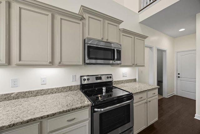 kitchen with light stone countertops, dark wood-type flooring, and appliances with stainless steel finishes