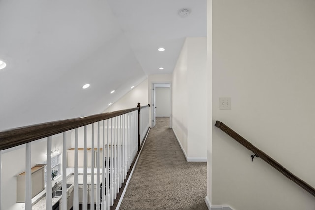 hallway with carpet floors and vaulted ceiling