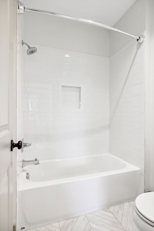 bathroom with tile patterned flooring, toilet, and tiled shower / bath