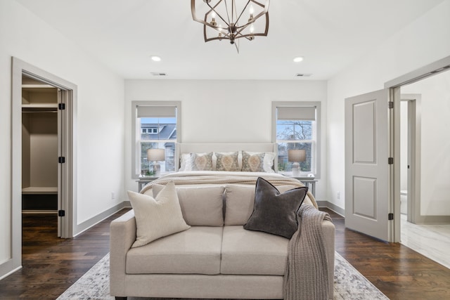 bedroom with an inviting chandelier, a spacious closet, a closet, and dark wood-type flooring