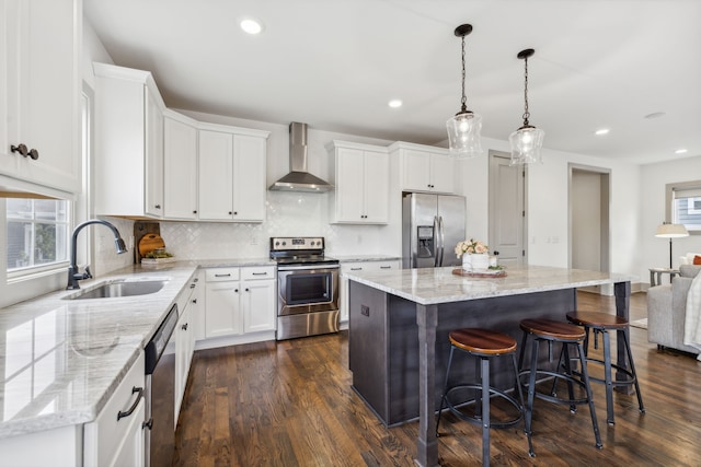 kitchen featuring a center island, wall chimney exhaust hood, stainless steel appliances, sink, and dark hardwood / wood-style flooring