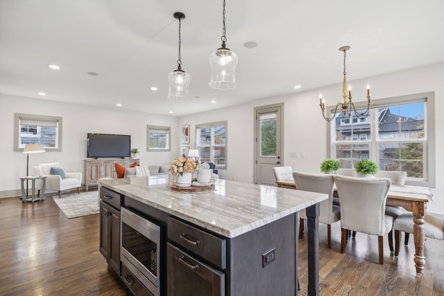 kitchen featuring stainless steel microwave, a center island, dark wood-type flooring, and decorative light fixtures