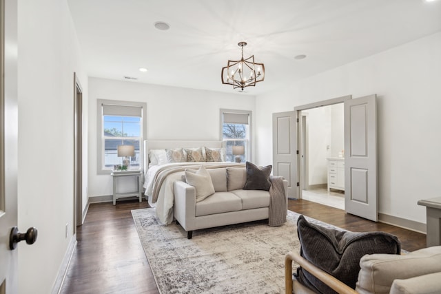 bedroom featuring dark hardwood / wood-style floors, a chandelier, connected bathroom, and multiple windows