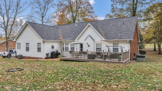 rear view of house featuring a lawn, central AC unit, and a wooden deck