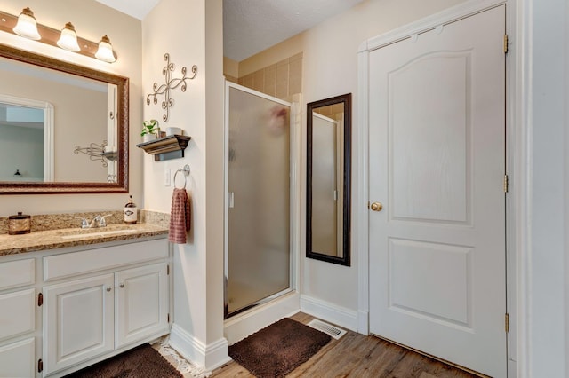 bathroom with vanity, a textured ceiling, hardwood / wood-style flooring, and walk in shower