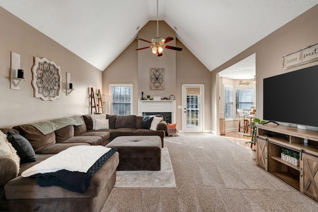 carpeted living room with ceiling fan and high vaulted ceiling