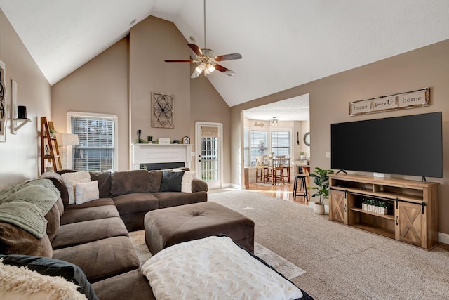 carpeted living room with ceiling fan and high vaulted ceiling