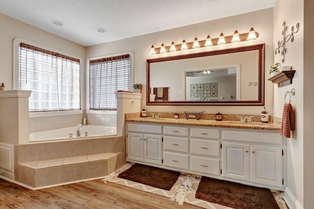 bathroom featuring tiled tub, vanity, and hardwood / wood-style flooring