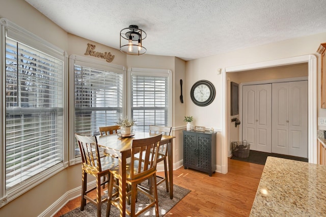 dining area featuring a textured ceiling and light hardwood / wood-style flooring