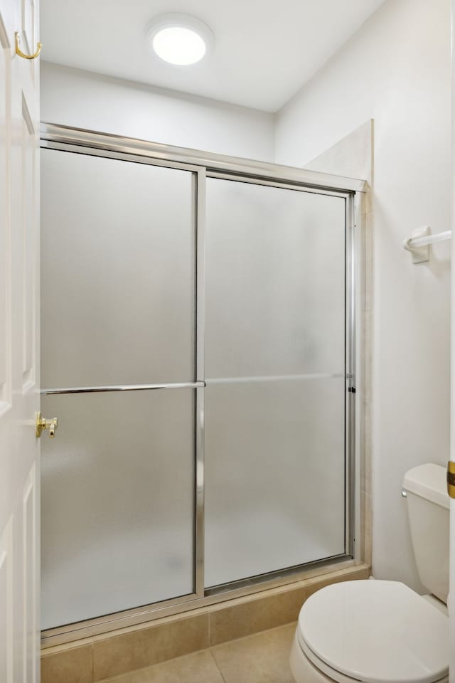 bathroom featuring tile patterned flooring, toilet, and an enclosed shower