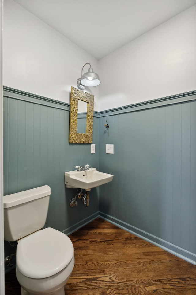 bathroom featuring wood walls, sink, wood-type flooring, and toilet