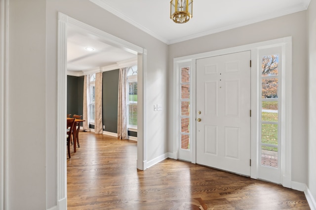 foyer entrance featuring crown molding, hardwood / wood-style floors, and a notable chandelier