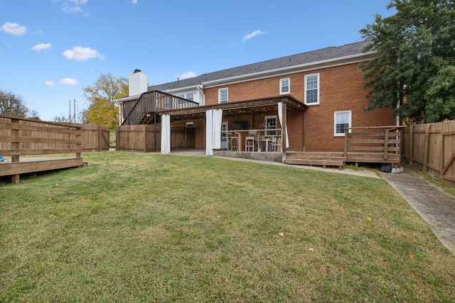 rear view of house featuring a bar, a deck, and a lawn