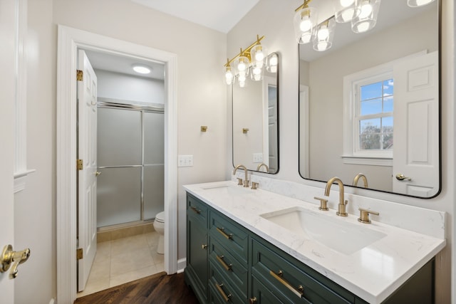 bathroom featuring toilet, wood-type flooring, a shower with door, and vanity