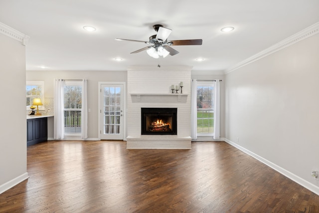 unfurnished living room featuring ceiling fan, dark hardwood / wood-style flooring, ornamental molding, and a fireplace