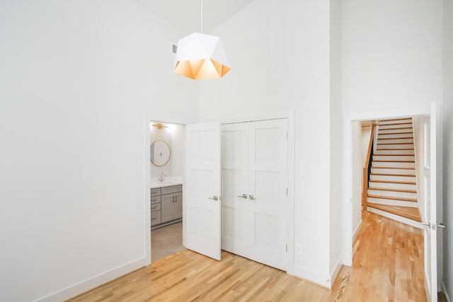 unfurnished bedroom with a closet, sink, high vaulted ceiling, and light hardwood / wood-style flooring