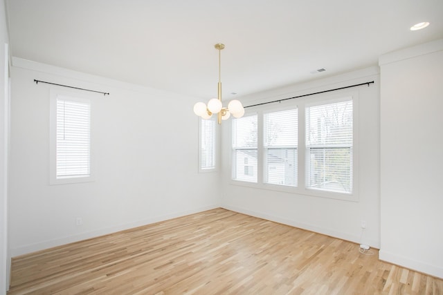 empty room with wood-type flooring and an inviting chandelier