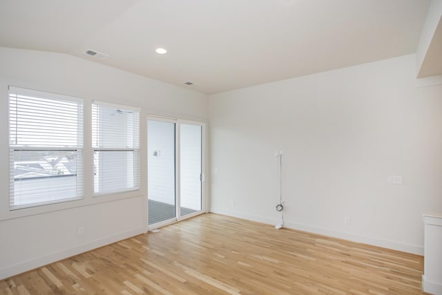 unfurnished room featuring lofted ceiling and light wood-type flooring