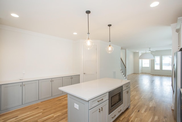 kitchen with pendant lighting, light hardwood / wood-style flooring, ceiling fan, gray cabinets, and appliances with stainless steel finishes