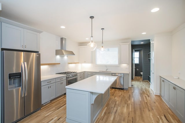 kitchen with a center island, ventilation hood, sink, light wood-type flooring, and appliances with stainless steel finishes