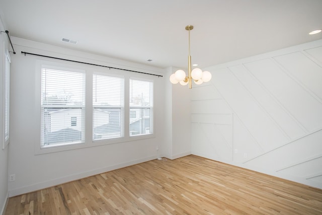 spare room featuring a chandelier and hardwood / wood-style flooring