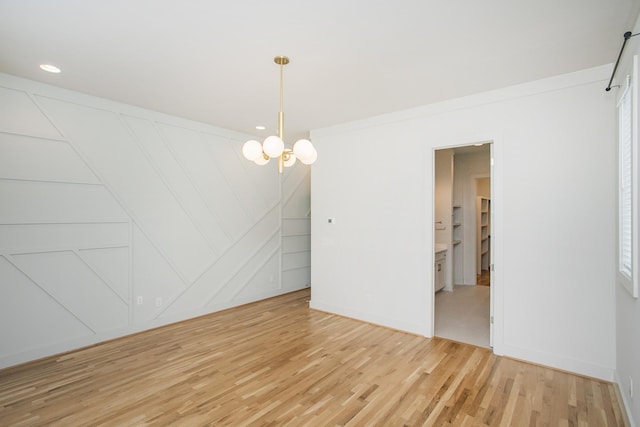 empty room featuring wood-type flooring and a chandelier