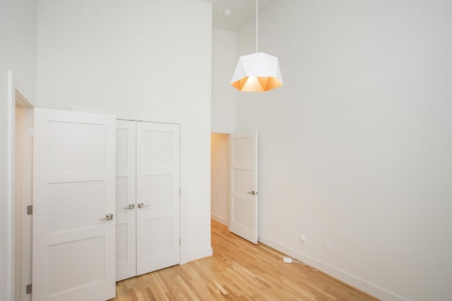 unfurnished bedroom with hardwood / wood-style flooring, a high ceiling, and a closet