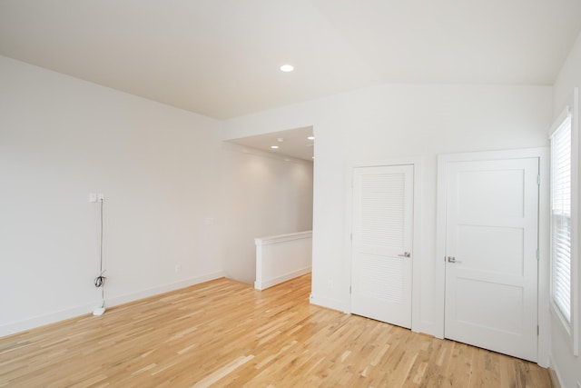 empty room with light hardwood / wood-style floors and vaulted ceiling