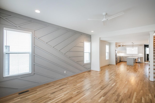 unfurnished living room featuring ceiling fan and light wood-type flooring