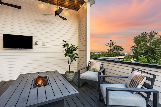 deck at dusk with a fire pit and ceiling fan