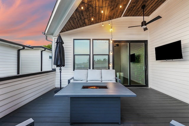 deck at dusk with a fire pit and ceiling fan