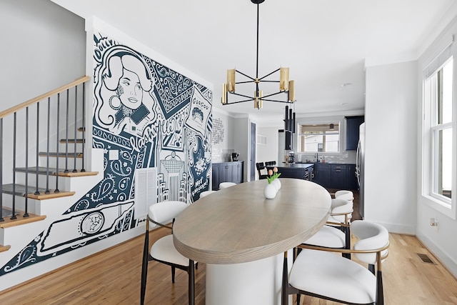 dining space with light wood-type flooring and an inviting chandelier