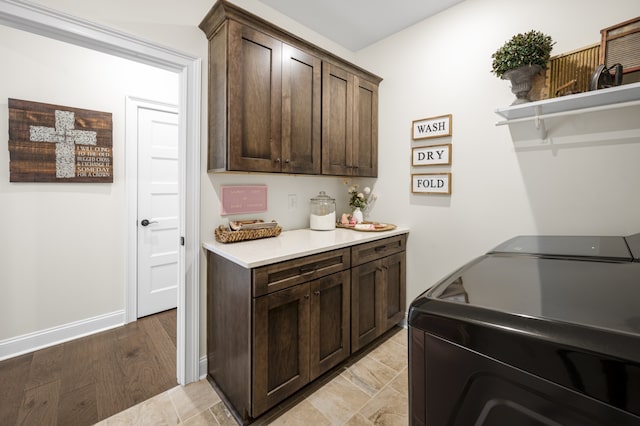 clothes washing area with washer and dryer, light hardwood / wood-style floors, and cabinets