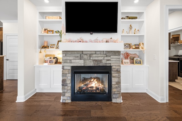 interior space featuring a stone fireplace, black electric range, hardwood / wood-style flooring, built in shelves, and ornamental molding