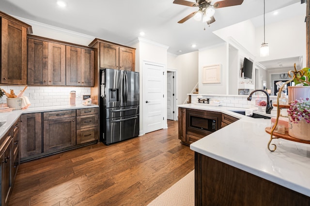 kitchen featuring black microwave, sink, dark hardwood / wood-style flooring, stainless steel refrigerator with ice dispenser, and pendant lighting