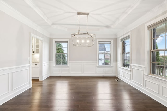 unfurnished dining area with a tray ceiling, dark hardwood / wood-style flooring, an inviting chandelier, and ornamental molding