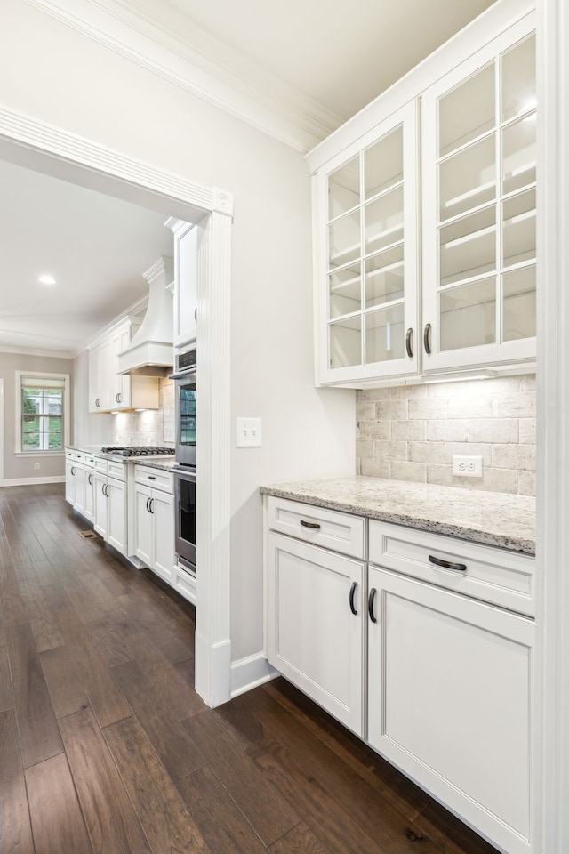 kitchen with white cabinetry, dark hardwood / wood-style flooring, custom range hood, and backsplash